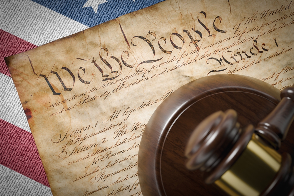 The united states constitution lying on an American flag with a gavel